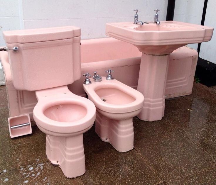 two pink toilets sitting next to each other in front of a bathtub and sink