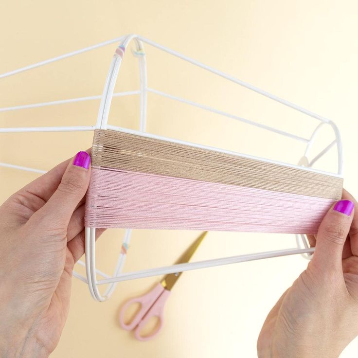 a pair of hands holding up some pink and white clothes pegs next to scissors