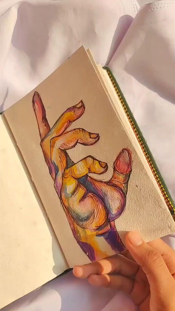 a hand holding an open book with a drawing of a dog's paw on it