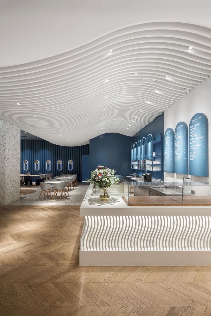 the interior of a store with blue walls and white wavy designs on the ceiling, along with wooden flooring