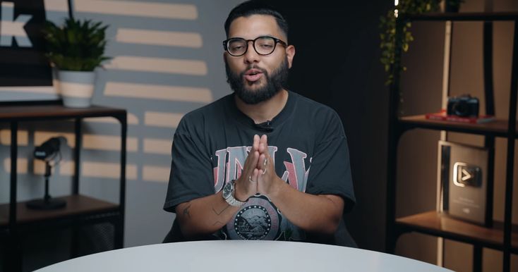 a man sitting at a table with his hands folded in front of him and looking surprised