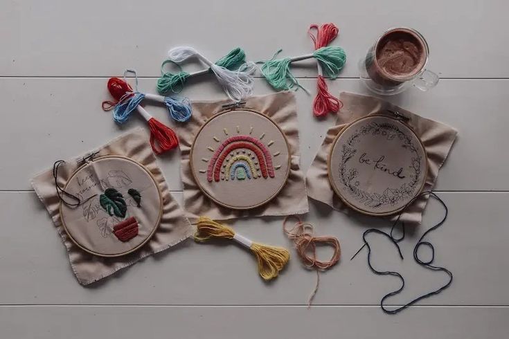 some embroiderys are laying on the floor next to scissors and thread spools