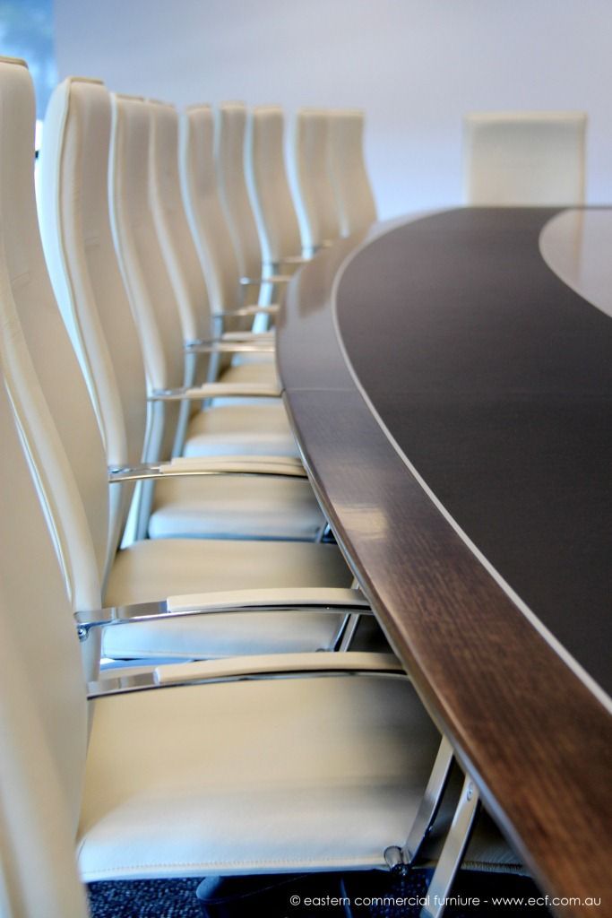 an empty conference table with white chairs around it