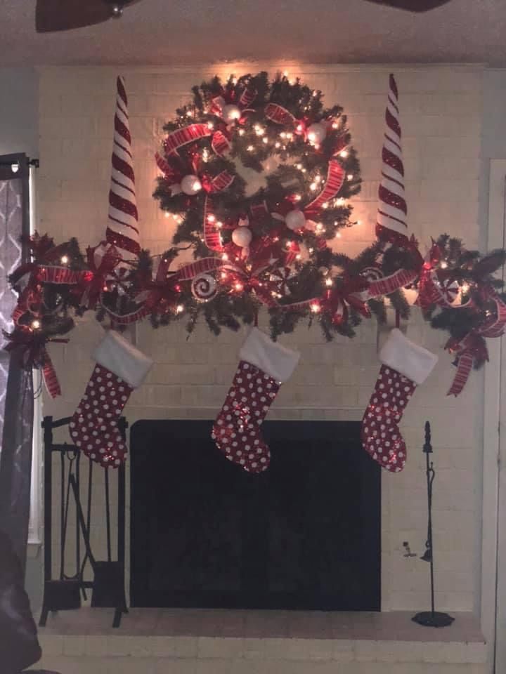 a decorated fireplace with stockings and stocking hanging from it's mantel in front of a christmas wreath