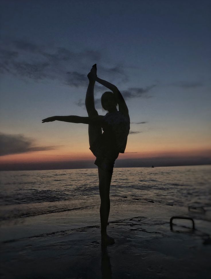 a person standing on the beach with their arms in the air while doing a handstand