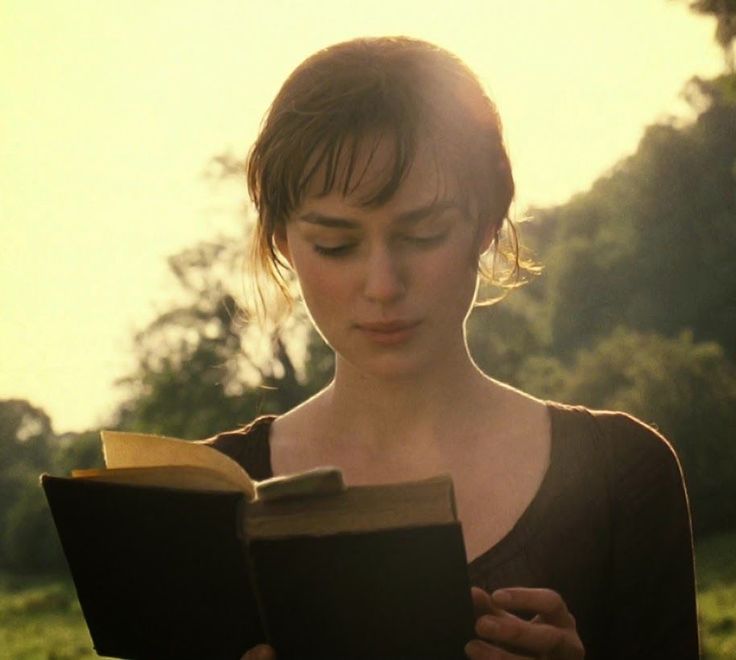 a woman is reading a book in the park at sunset or sunrise, with her eyes closed