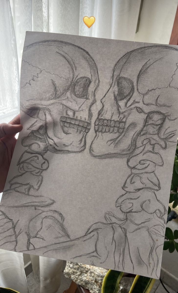 someone holding up a drawing of two skulls