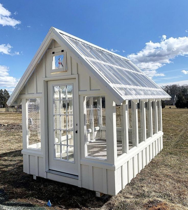 a small white house sitting in the middle of a field