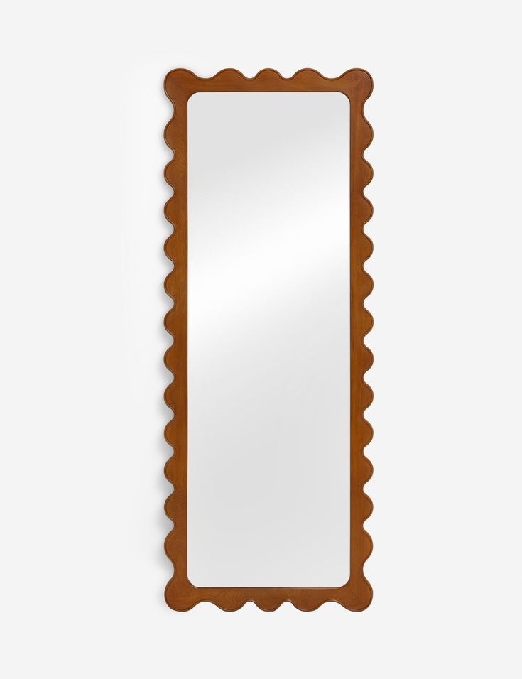 a mirror with scalloped edges and a wooden frame on the wall, against a white background