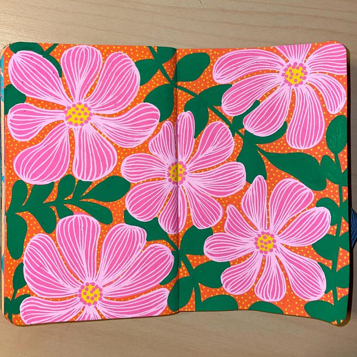 an open notebook with pink flowers painted on the inside and green leaves in the middle