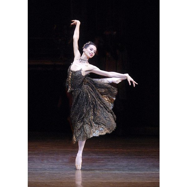 a ballerina in black and gold dress on stage