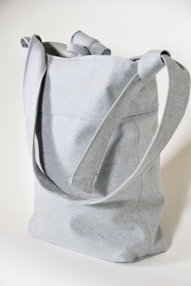 a gray tote bag sitting on top of a white table