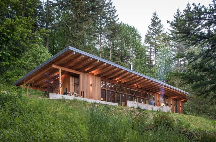 the house is on top of a hill in the middle of some trees and grass