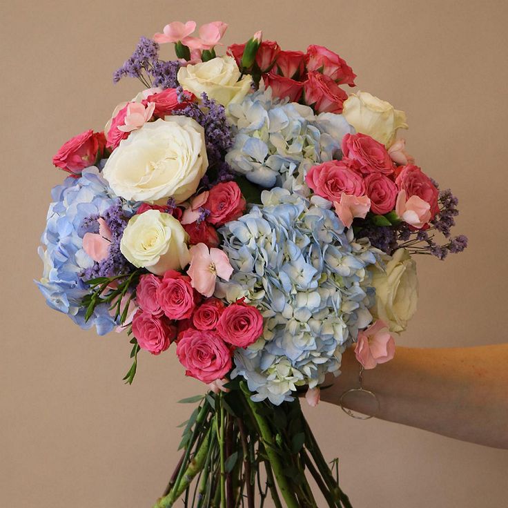 a person holding a bouquet of flowers in their hand with the other hand on it