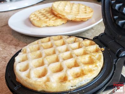 two waffles sitting on top of a black plate next to another white plate