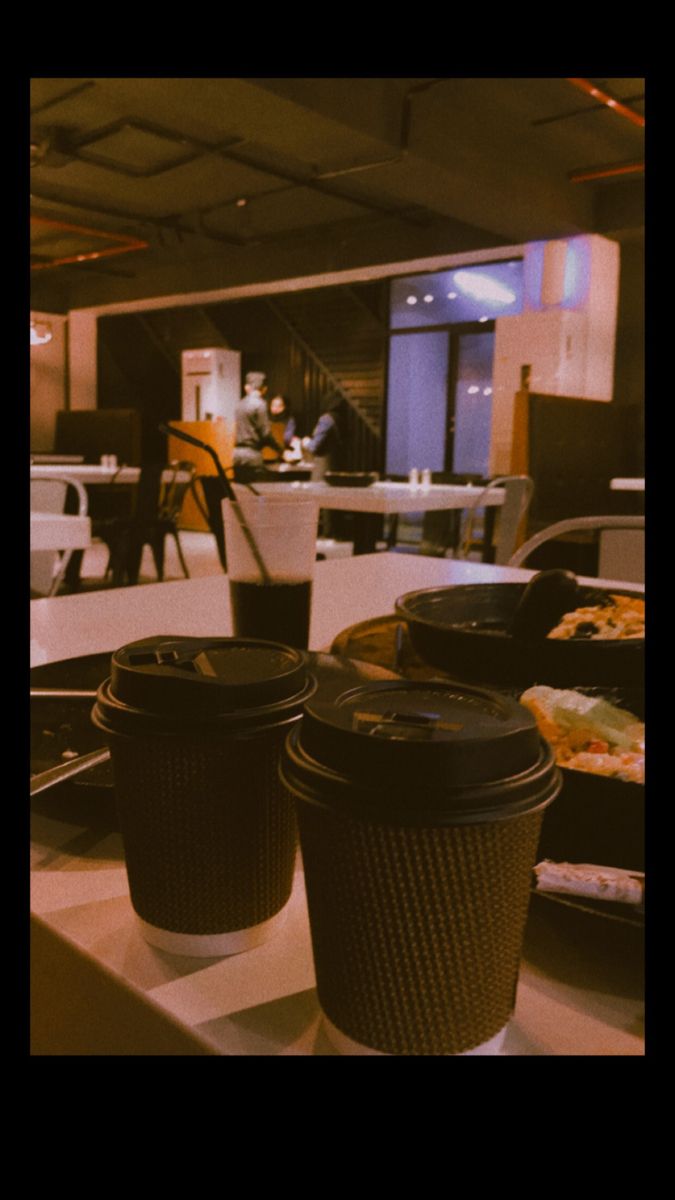 two coffee cups sitting on top of a counter next to each other in front of a table