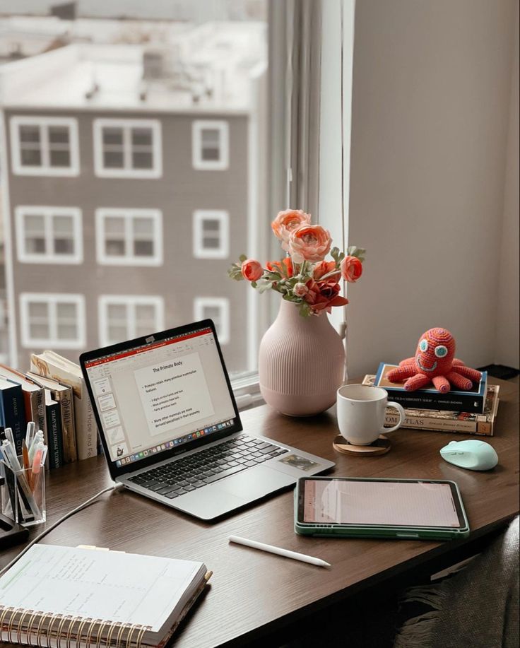 an open laptop computer sitting on top of a wooden desk next to a cup of coffee