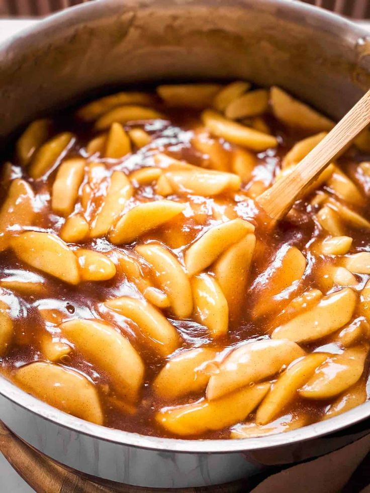 a pot filled with macaroni and cheese being stirred by a wooden spoon in it