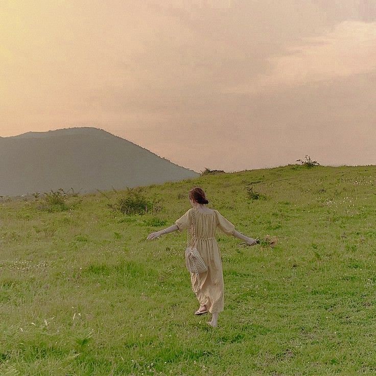 a woman walking across a lush green field