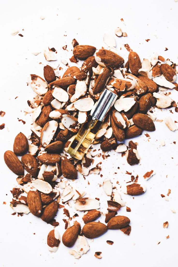 almonds and nuts are scattered on top of a white surface, with a lighter in the middle