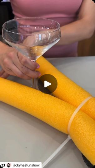 a woman holding a wine glass next to two large yellow objects on top of a table