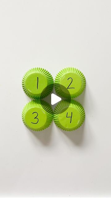 four green cupcake cases sitting on top of a white surface with numbers in the middle