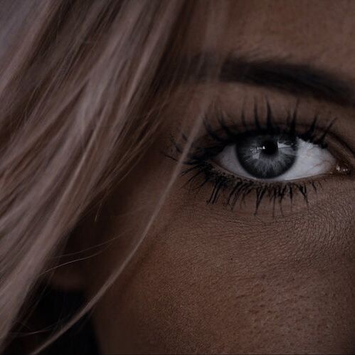 a woman's eye with long hair and blue eyes