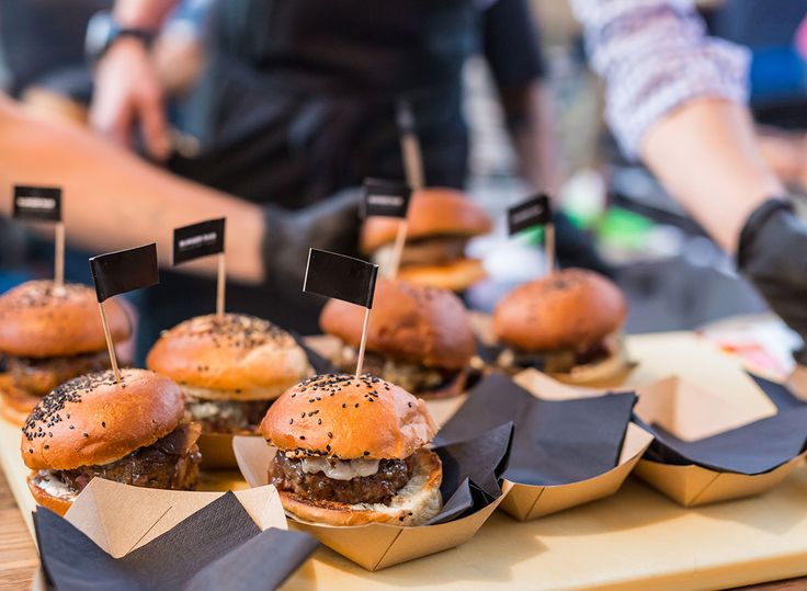 mini burgers with black flags on them are ready to be served at an event