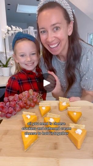 a woman and her daughter are smiling at the camera while making cheeses on a cutting board