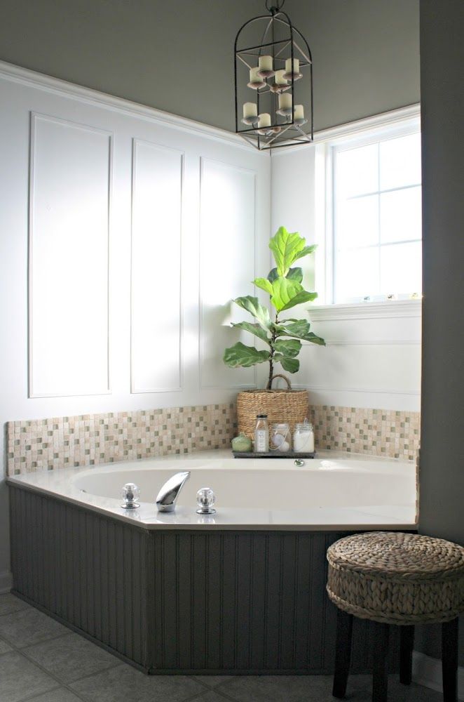 a bathroom with a large jacuzzi tub next to a stool and potted plant