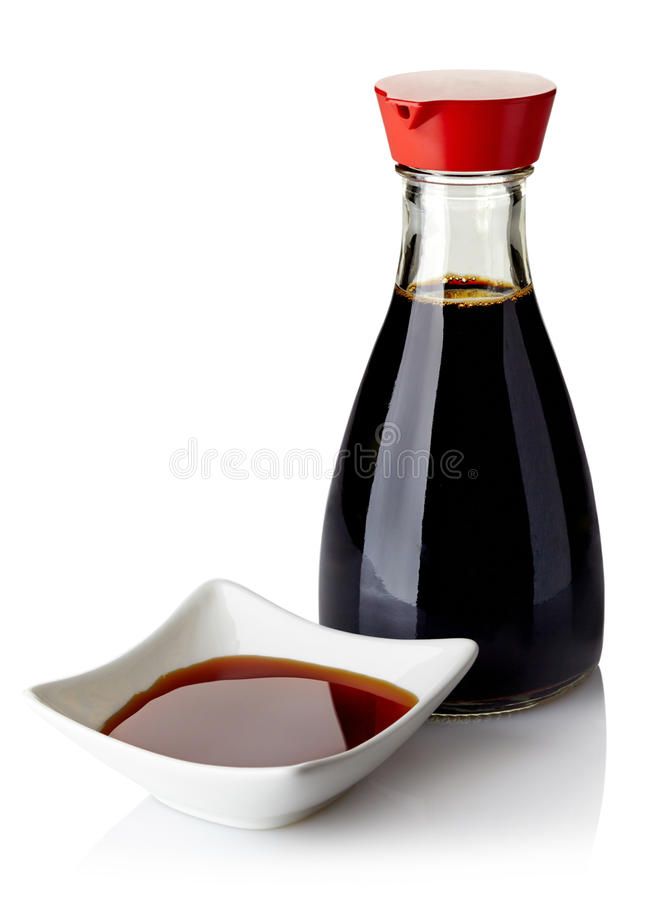 a bottle of ketchup next to a small bowl with sauce in it on a white surface