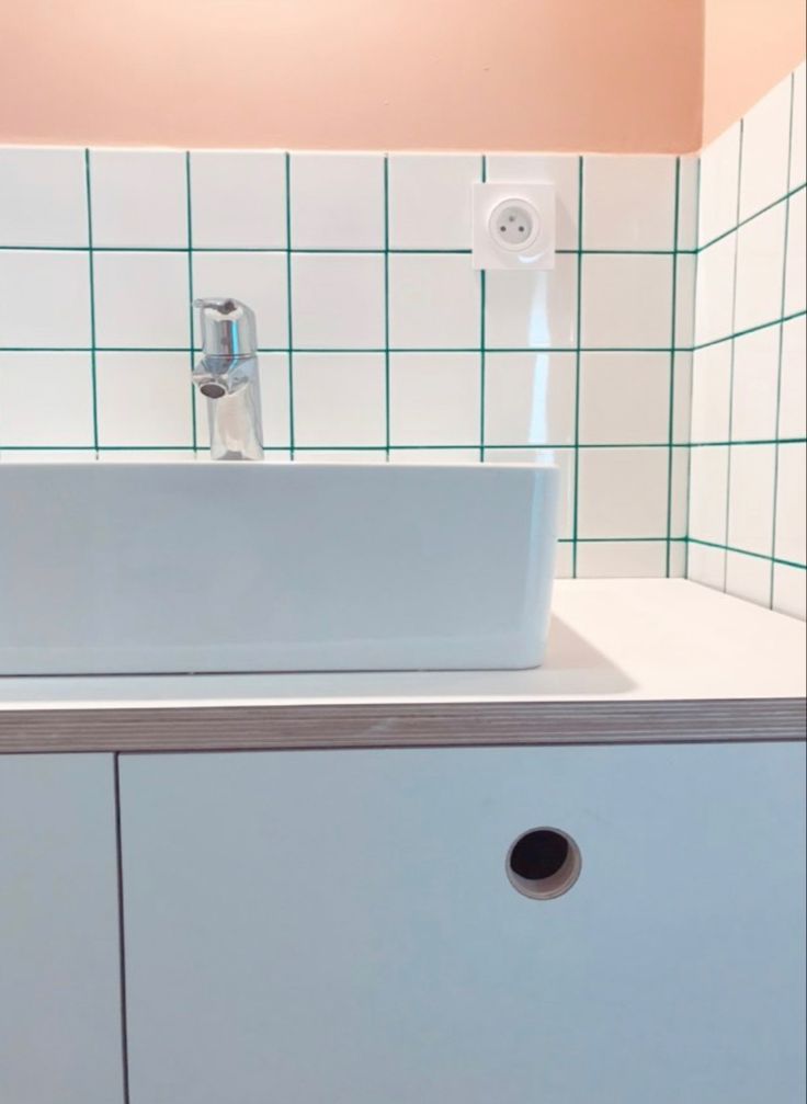 a white sink sitting on top of a counter next to a wall mounted faucet