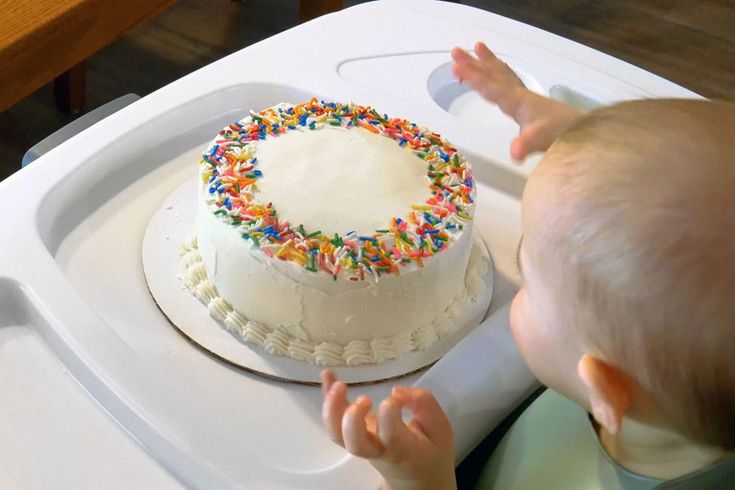 a baby reaching for a cake with sprinkles on it