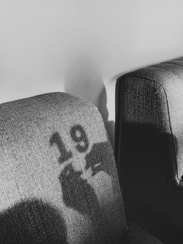 a black and white photo of two couches with the shadow of a person on them