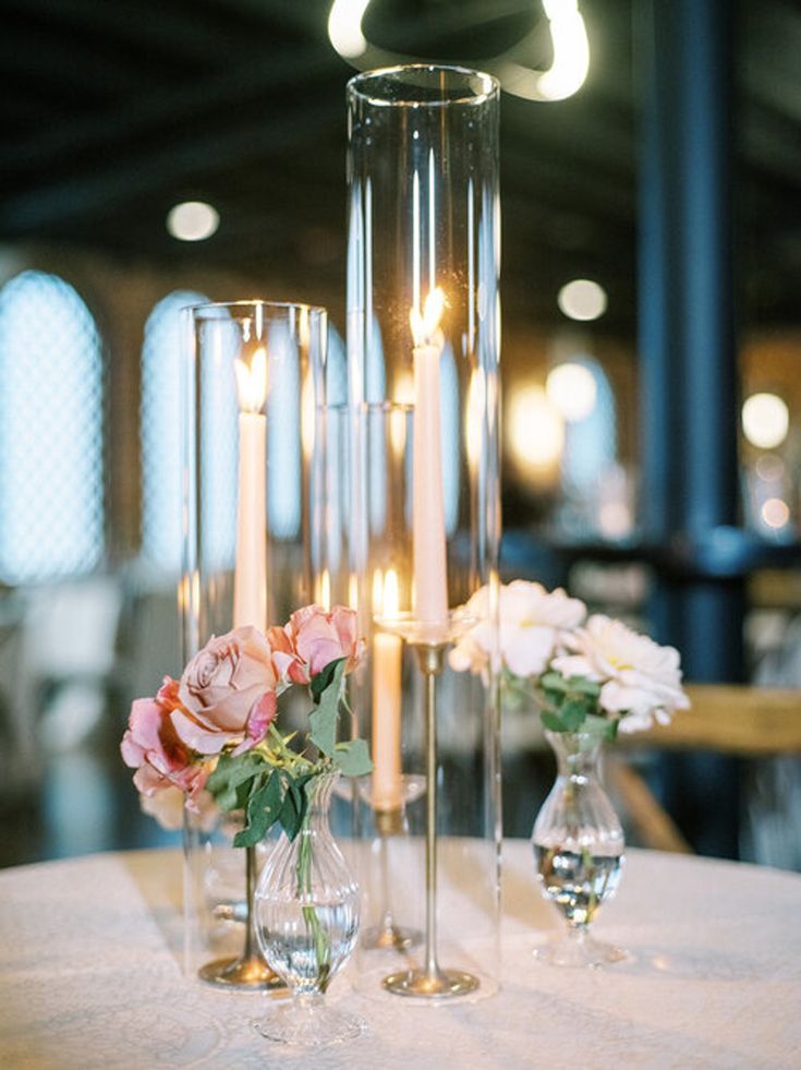 three tall vases filled with flowers on top of a table