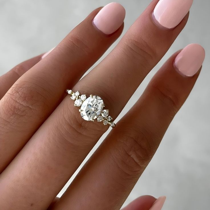 a woman's hand holding a ring with three stones on it and two fingers