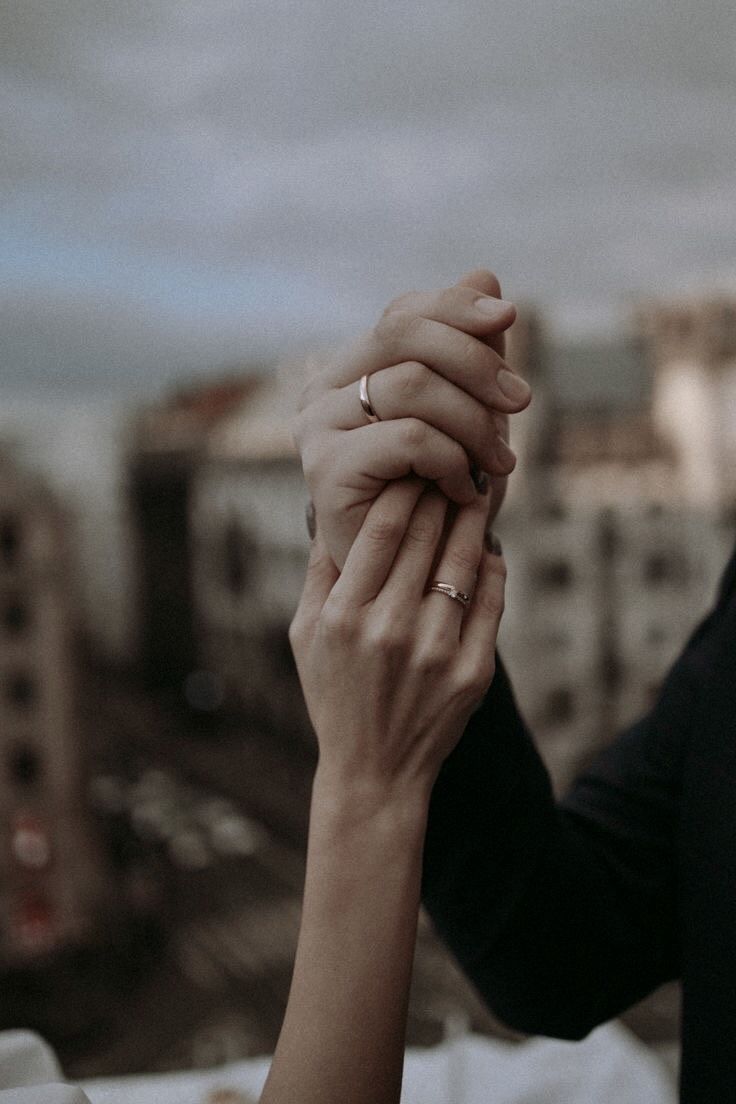 two people holding hands with buildings in the background