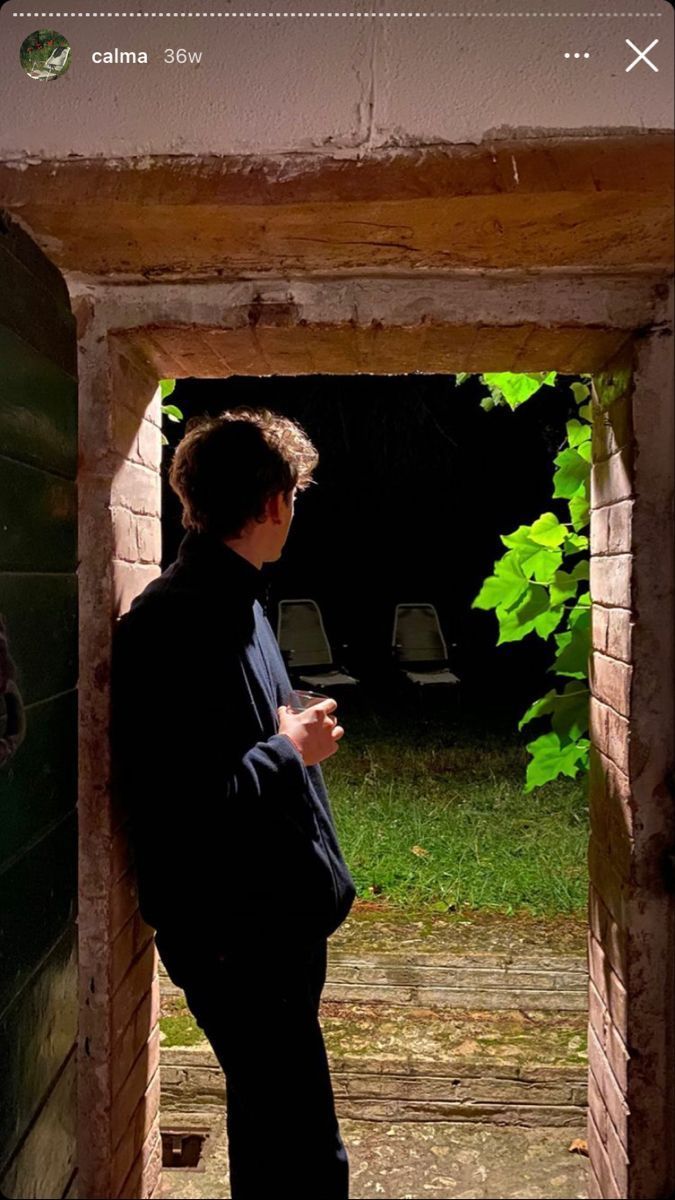 a man standing in an open doorway looking at his cell phone