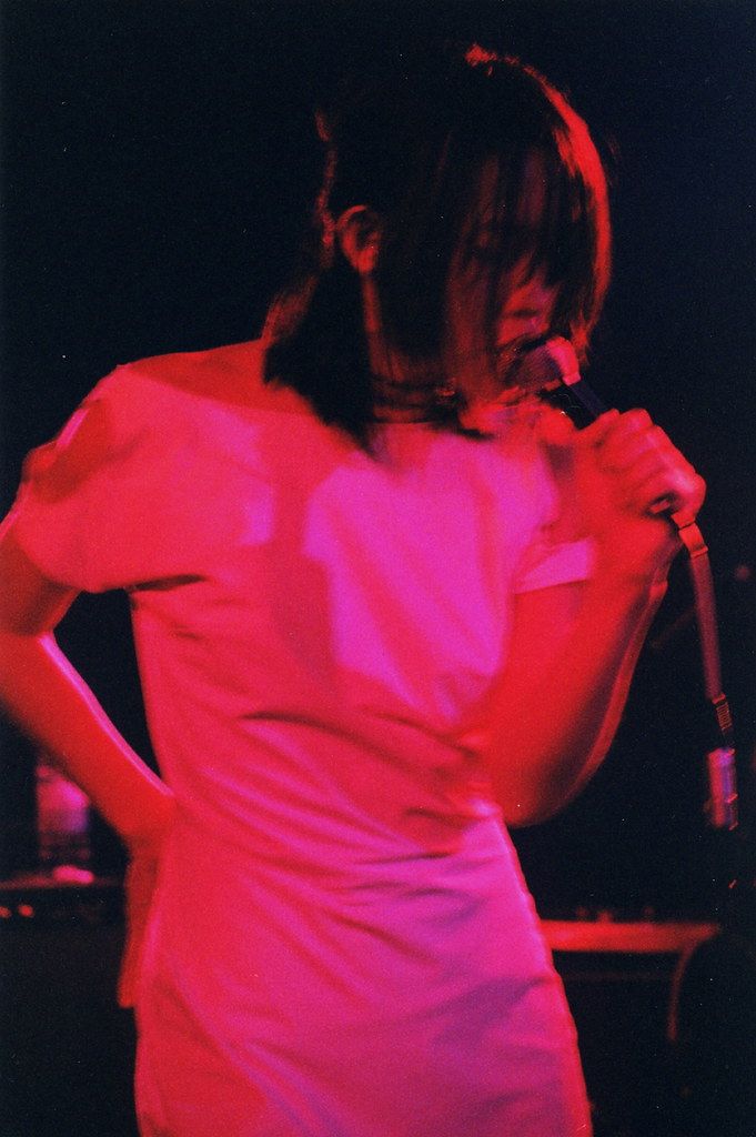 a woman standing in front of a microphone with her hands on her hips while wearing a pink dress