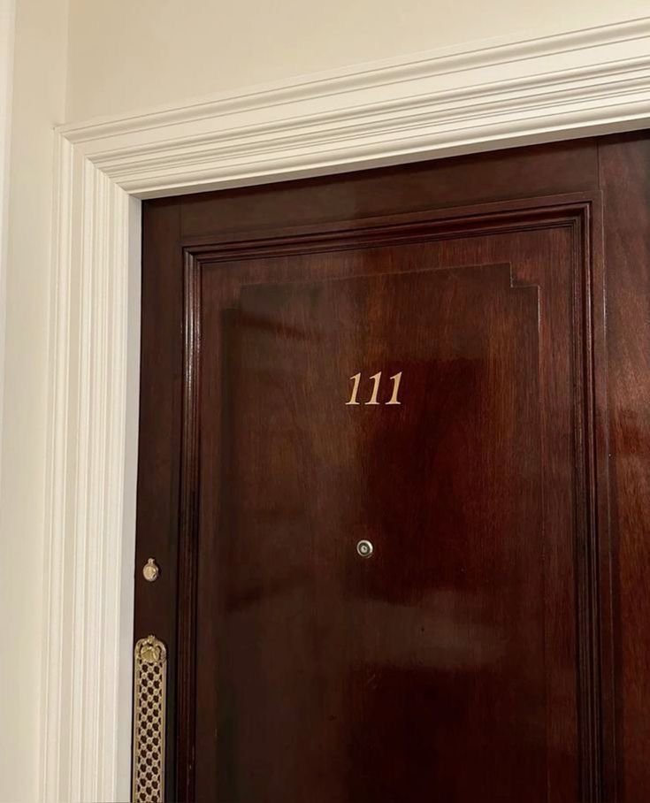 a wooden door with the number 11 on it in front of a white wall and doorway