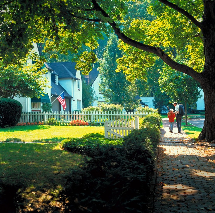 two people walking down a path in front of a house