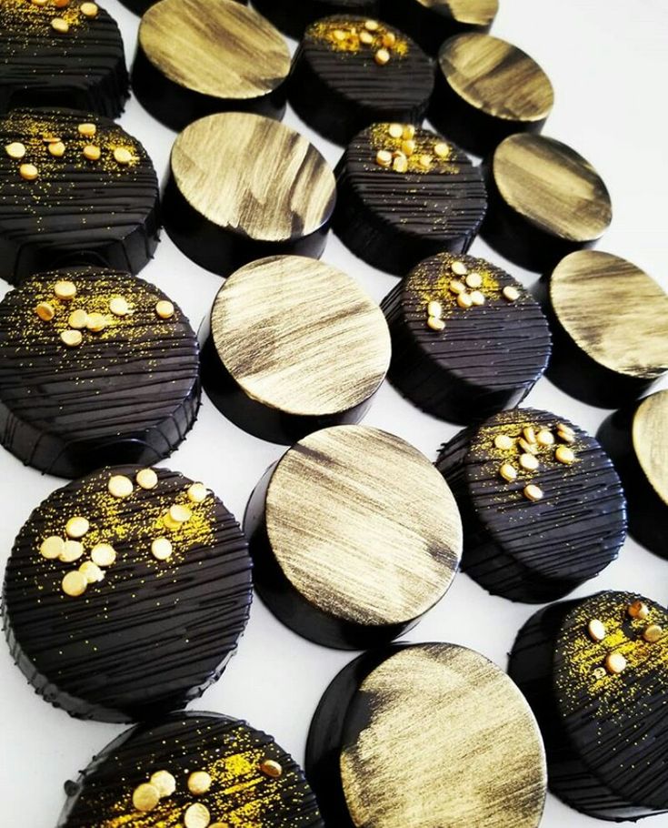 some black and gold decorated cookies on a white table