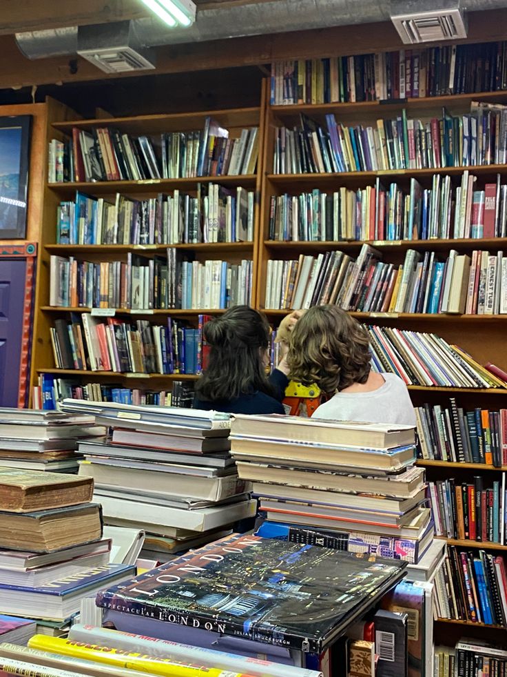 two people sitting in front of a book shelf filled with books