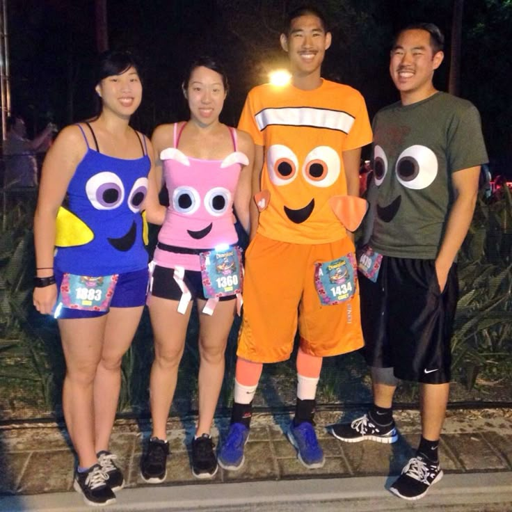 four people dressed up in costumes standing next to each other on the street at night