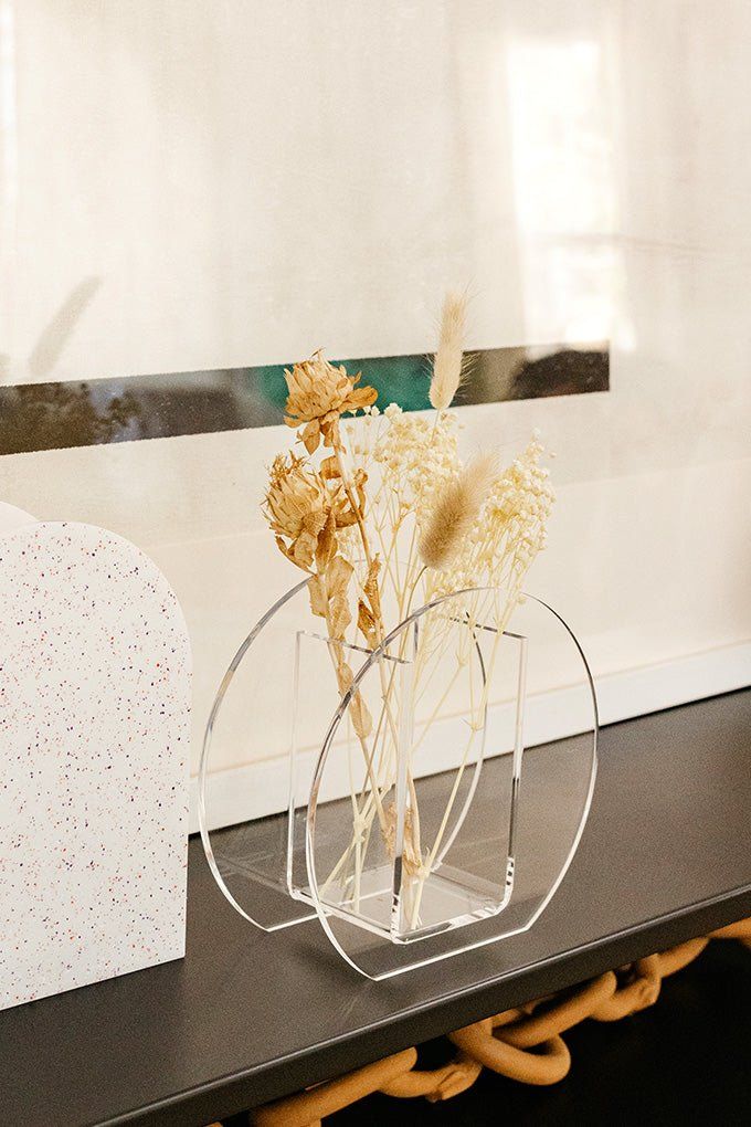 a vase with dried flowers in it sitting on a table next to a card board