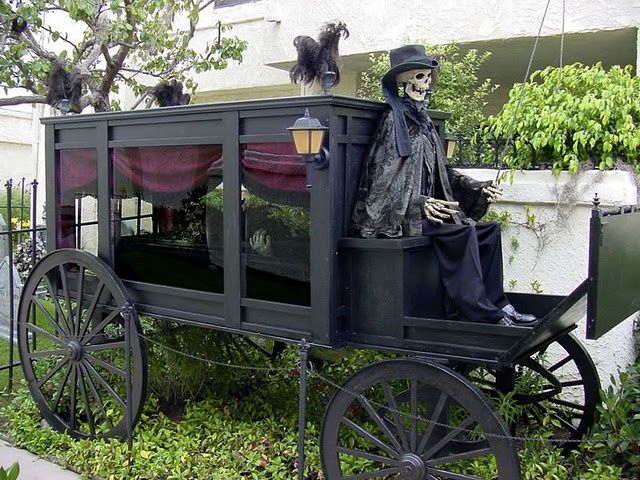 a skeleton sitting on top of a horse drawn carriage