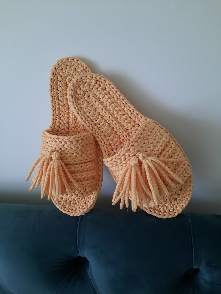 a pair of crocheted slippers sitting on top of a blue couch