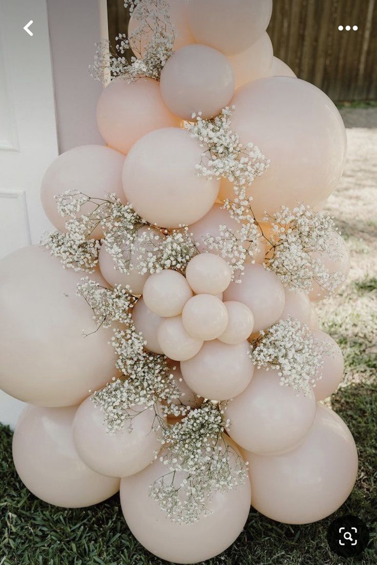 a bunch of balloons that are in the grass with some flowers on top of them