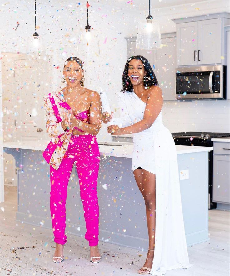 two women standing in a kitchen with confetti all over them