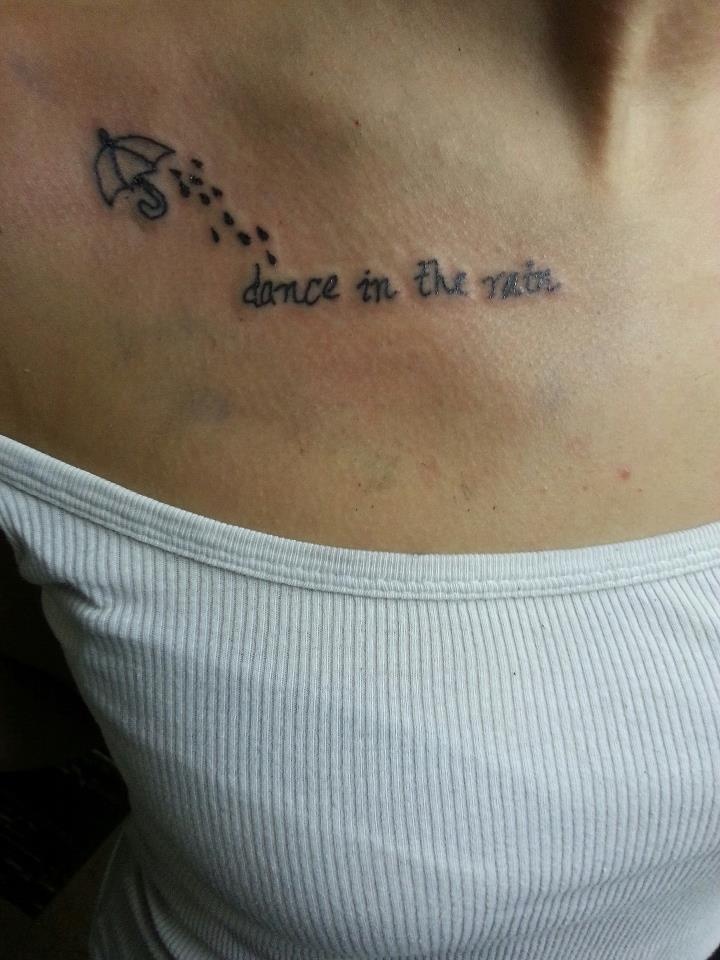 a woman with a tattoo on her chest that says dance in the rain and an umbrella